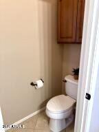 bathroom with tile patterned floors, baseboards, and toilet