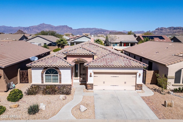 mediterranean / spanish house featuring concrete driveway, a mountain view, and stone siding