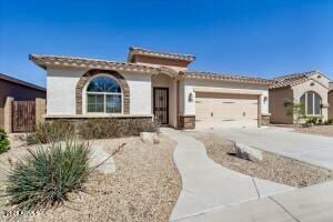 mediterranean / spanish-style home with stucco siding, an attached garage, and driveway