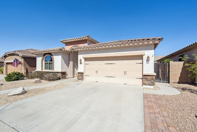 mediterranean / spanish-style home featuring stucco siding, stone siding, concrete driveway, an attached garage, and a tiled roof