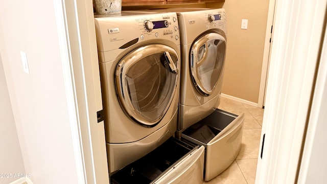 laundry area featuring laundry area, light tile patterned flooring, baseboards, and washer and clothes dryer