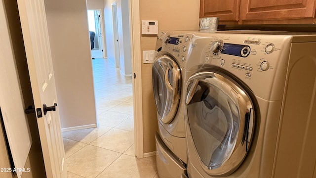 laundry area featuring washer and clothes dryer, cabinet space, and light tile patterned flooring