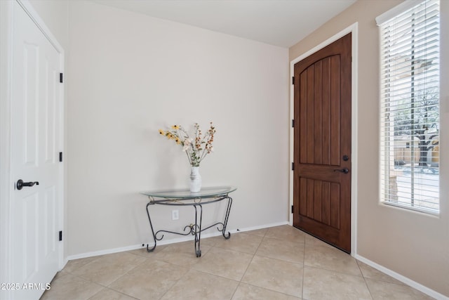 foyer entrance with light tile patterned floors and baseboards