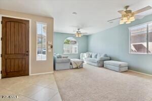 living area featuring baseboards, ceiling fan, and tile patterned flooring