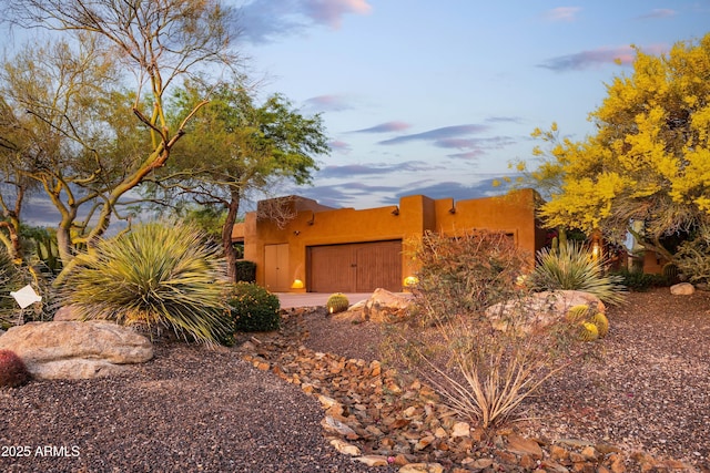 adobe home with an attached garage and driveway