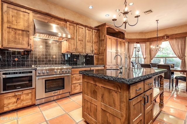 kitchen featuring stainless steel appliances, wall chimney range hood, visible vents, a sink, and a notable chandelier