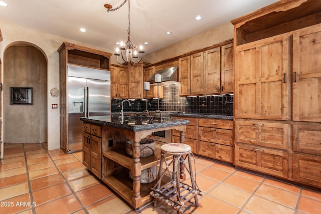 kitchen featuring open shelves, built in refrigerator, wall chimney exhaust hood, and recessed lighting