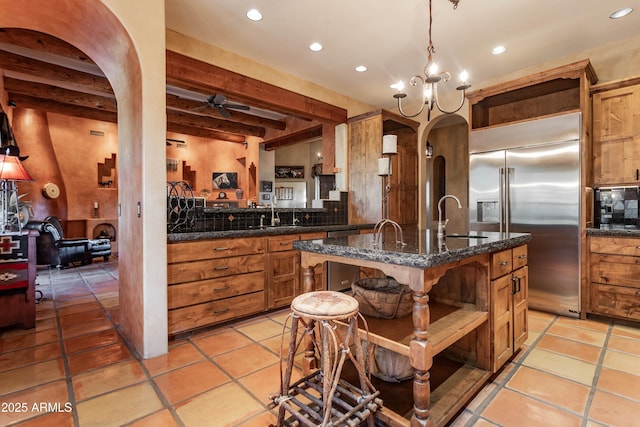 kitchen with recessed lighting, open shelves, a sink, arched walkways, and stainless steel built in fridge