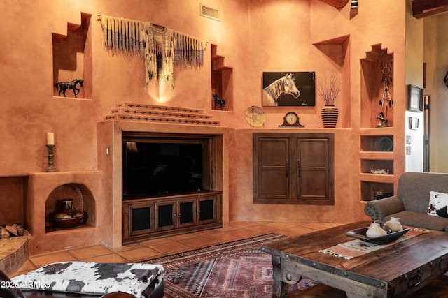 living area featuring a towering ceiling, visible vents, tile patterned flooring, and built in features