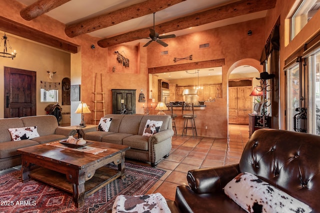 living area with a high ceiling, visible vents, a ceiling fan, light tile patterned floors, and arched walkways