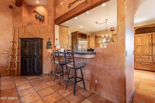 kitchen featuring tile patterned floors, arched walkways, stainless steel built in fridge, open shelves, and a breakfast bar