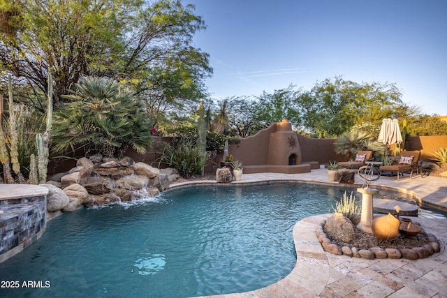 view of swimming pool featuring exterior fireplace, fence, a patio area, and a fenced in pool