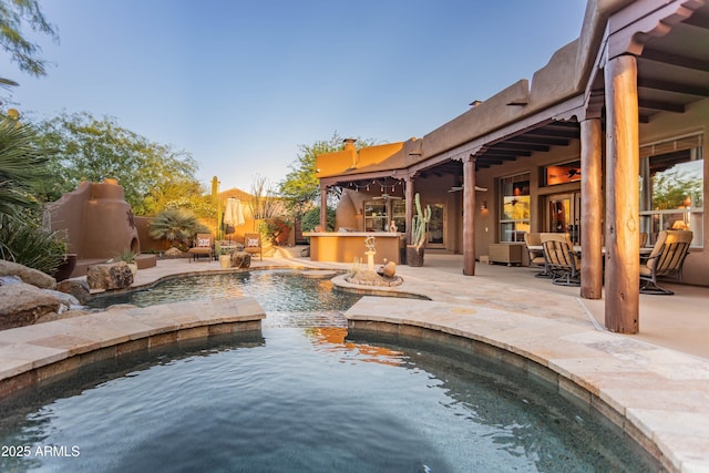 pool featuring fence, a patio area, and exterior kitchen