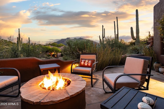 view of patio featuring an outdoor fire pit and a mountain view