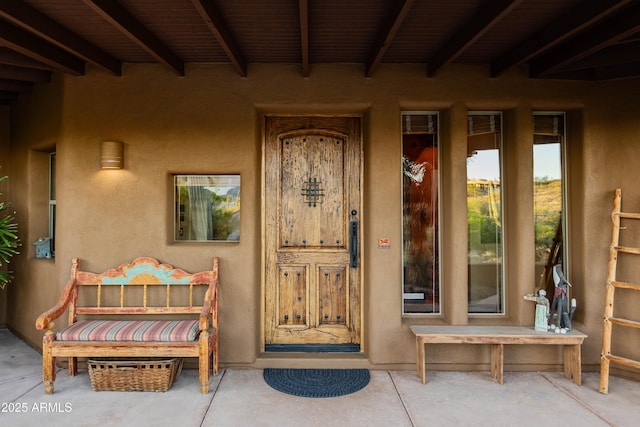 entrance to property featuring covered porch and stucco siding