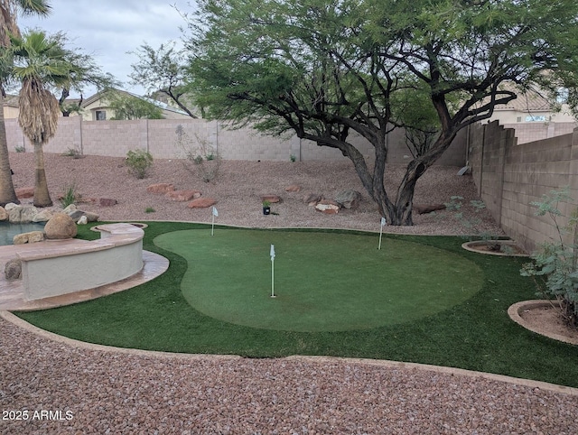 view of community with a putting green and a fenced backyard