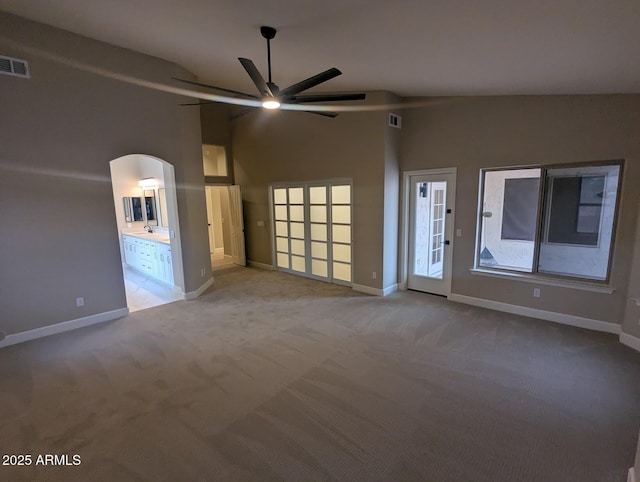 carpeted spare room with ceiling fan, baseboards, arched walkways, and high vaulted ceiling