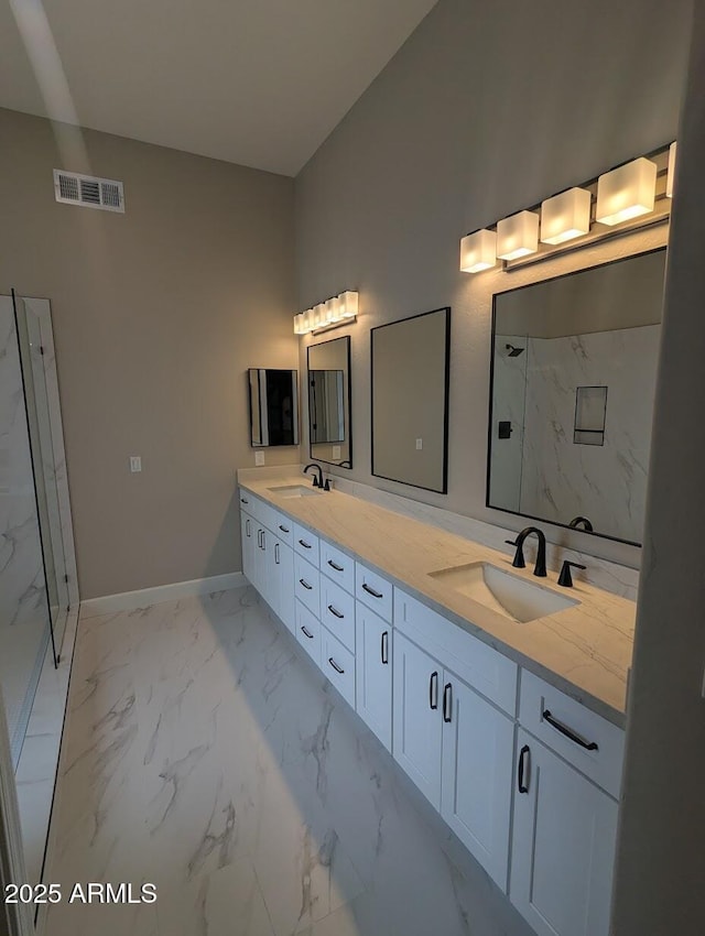 bathroom with marble look tile flooring, baseboards, double vanity, and a marble finish shower