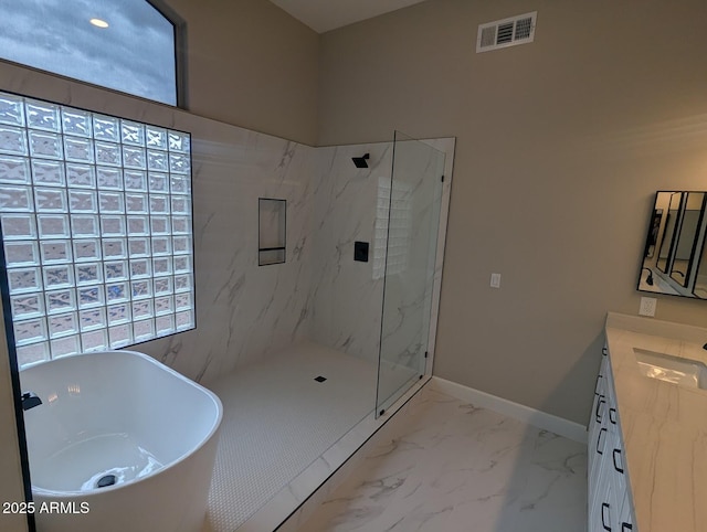 full bath with a marble finish shower, a freestanding tub, vanity, marble look tiles, and baseboards