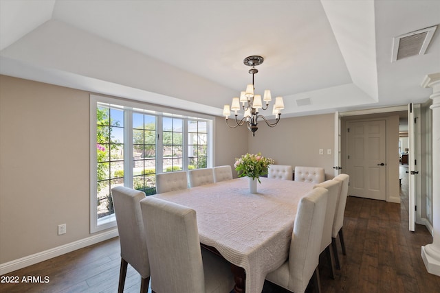 dining space with a raised ceiling, dark wood-type flooring, and an inviting chandelier