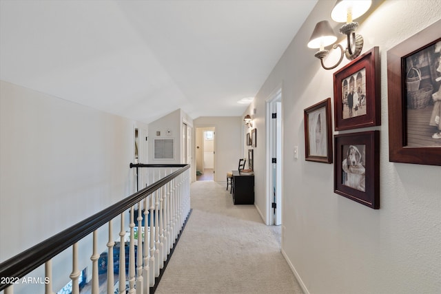 hallway with light carpet, vaulted ceiling, and an inviting chandelier