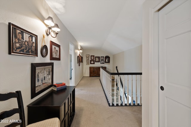 hallway with lofted ceiling and light colored carpet