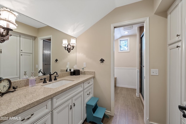 bathroom with hardwood / wood-style flooring, lofted ceiling, an inviting chandelier, and vanity