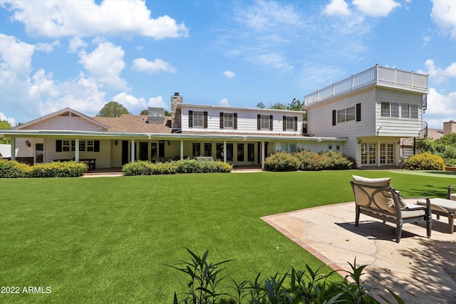 back of property with a patio, a yard, and french doors