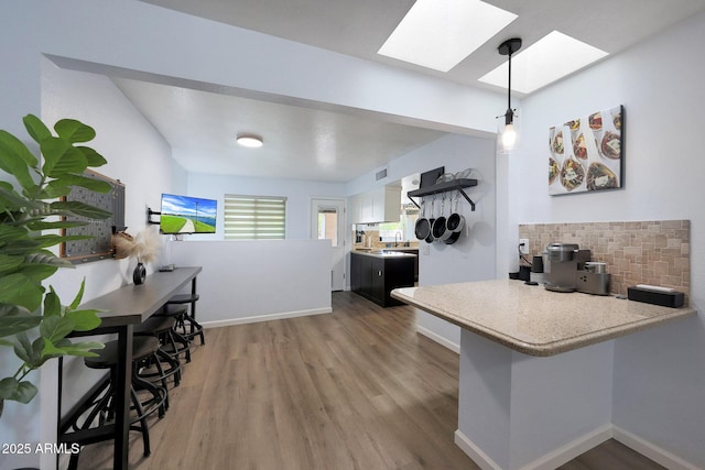 1444 E Myrna Ln, Tempe, AZ 85284 - kitchen featuring a skylight, tasteful backsplash, wood finished floors, light countertops, and white cabinetry