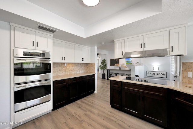 1444 E Myrna Ln, Tempe, AZ 85284 - kitchen featuring double oven, under cabinet range hood, black electric stovetop, tasteful backsplash, and white cabinetry