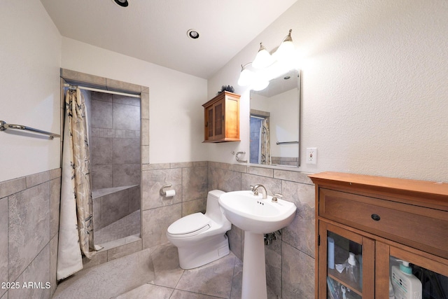 1444 E Myrna Ln, Tempe, AZ 85284 - bathroom with tile walls, a tile shower, toilet, tile patterned flooring, and a wainscoted wall