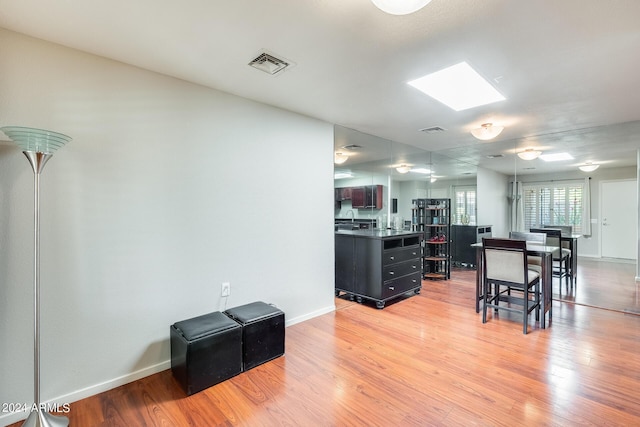 kitchen with a skylight, visible vents, dark countertops, and light wood-style flooring