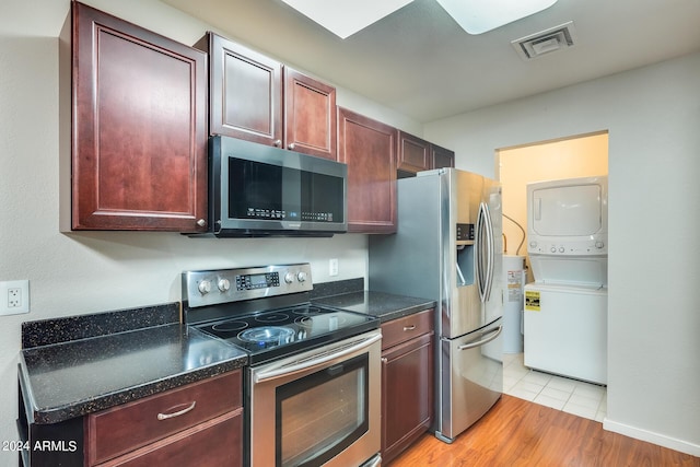 kitchen with visible vents, light wood finished floors, dark brown cabinets, stacked washer and clothes dryer, and appliances with stainless steel finishes