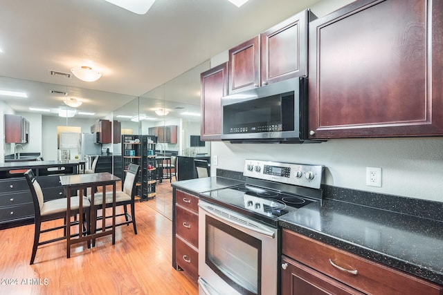 kitchen with dark countertops, visible vents, light wood-style floors, stainless steel appliances, and a sink