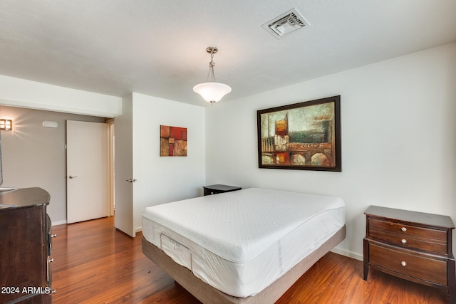 bedroom featuring visible vents, baseboards, and wood finished floors