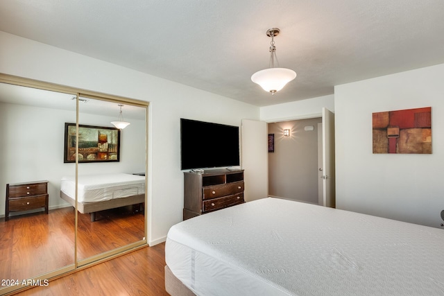 bedroom with visible vents, wood finished floors, a closet, and baseboards