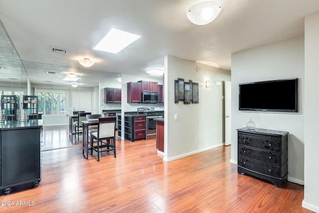 interior space with dark countertops, appliances with stainless steel finishes, light wood-type flooring, and baseboards