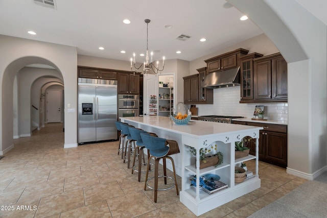 9608 N 184th Ln, Waddell, AZ 85355 - kitchen with stainless steel appliances, under cabinet range hood, arched walkways, open shelves, and light countertops