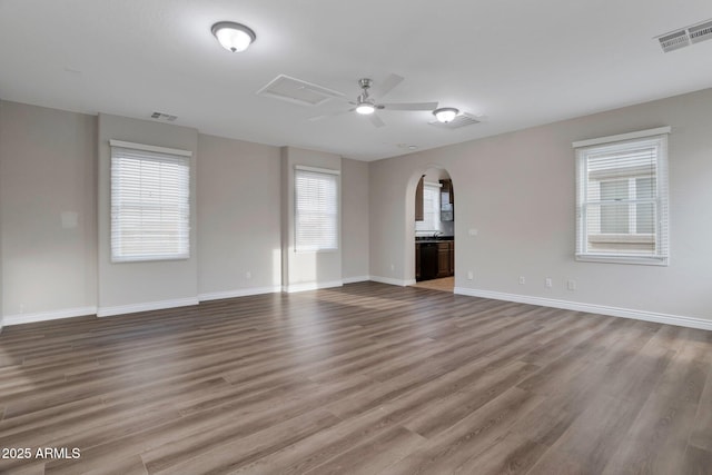 9608 N 184th Ln, Waddell, AZ 85355 - unfurnished living room with arched walkways, wood finished floors, ceiling fan, and baseboards