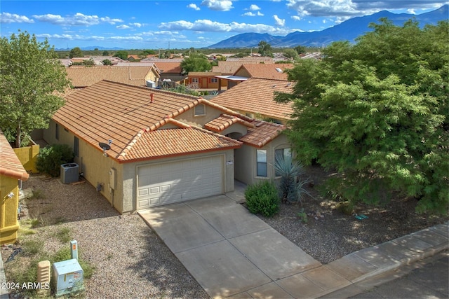 view of front of home featuring a mountain view, central AC unit, and a garage