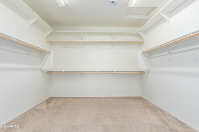 walk in closet featuring light colored carpet