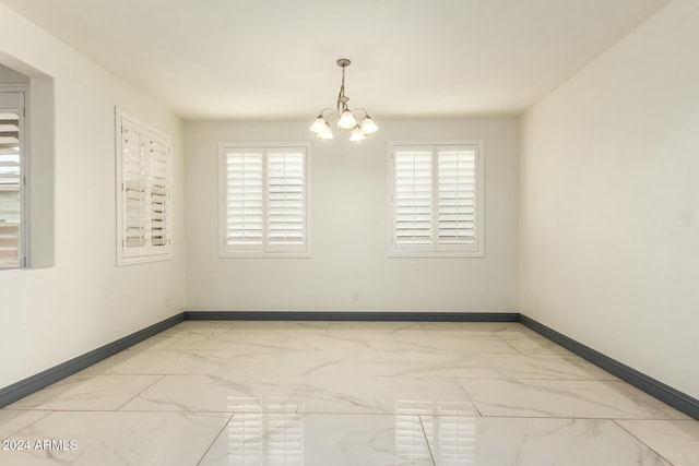 unfurnished room featuring a wealth of natural light and a notable chandelier