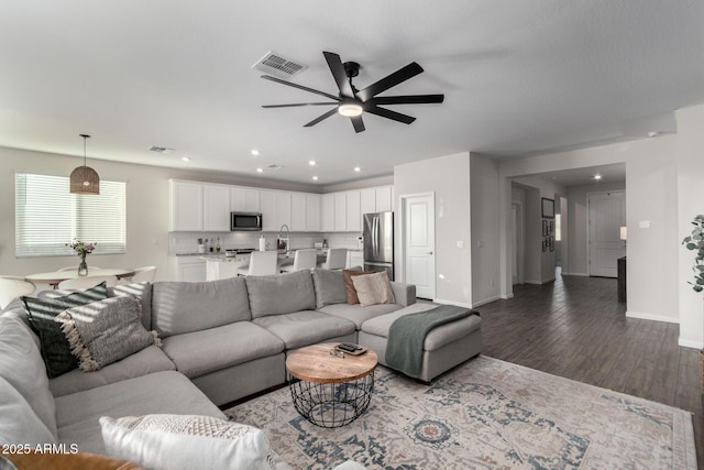 living room featuring sink, hardwood / wood-style flooring, and ceiling fan