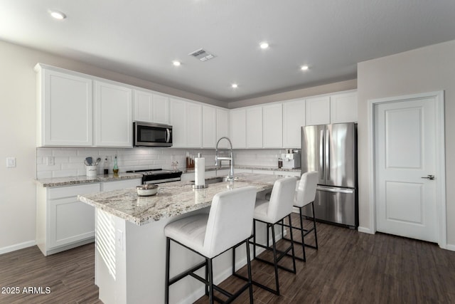 kitchen featuring an island with sink, white cabinetry, dark hardwood / wood-style floors, and appliances with stainless steel finishes