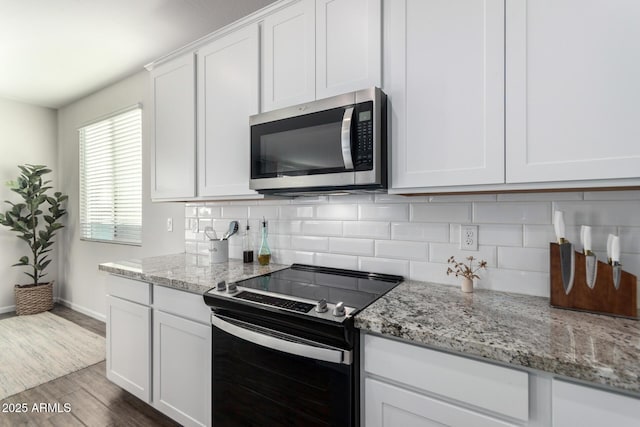 kitchen with hardwood / wood-style floors, white cabinets, light stone countertops, and appliances with stainless steel finishes