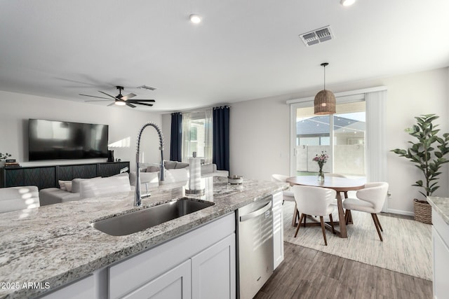 kitchen with pendant lighting, white cabinets, dark wood-type flooring, sink, and stainless steel dishwasher