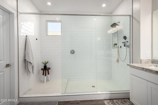 bathroom with a shower with shower door, hardwood / wood-style flooring, and vanity