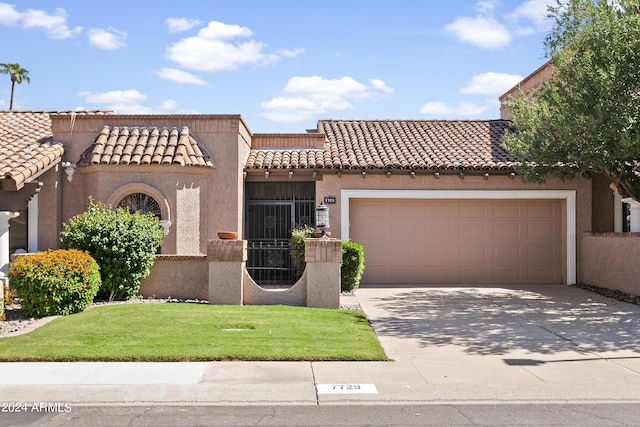 mediterranean / spanish home featuring a garage and a front lawn