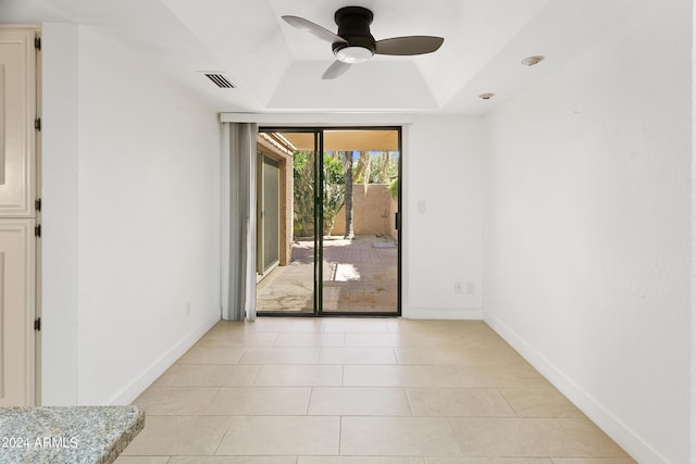 tiled spare room featuring ceiling fan and a raised ceiling