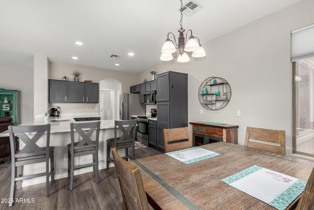 dining space featuring sink, dark wood-type flooring, and a chandelier